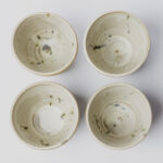 ceramiczne kubeczki z beżowej gliny szkliwione szaro-piaskowym szkliwem pochlapane na niebiesko-zielono