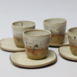 ceramiczne kubeczki z beżowej gliny szkliwione szaro-piaskowym szkliwem pochlapane na grafitowo z niebiesko-zielonymi przebarwieniami