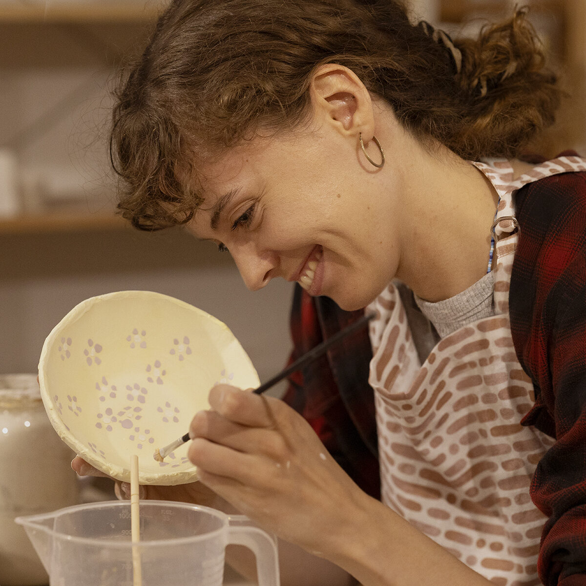 Uśmiechnięta dziewczyna szkliwi telerz ceramiczny
